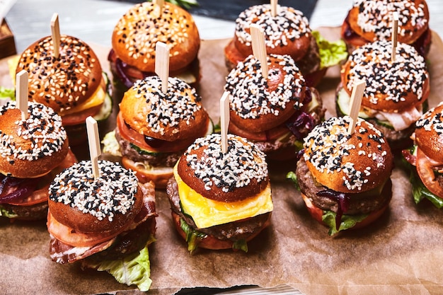 Foto un gran conjunto de muchas hamburguesas cheeseburgers colocadas en la mesa seth comida rápida de fondo