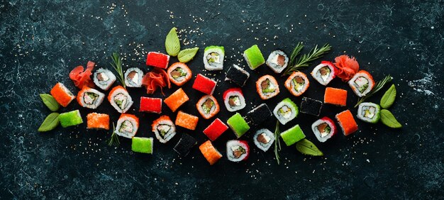 Gran conjunto de piezas de rollos de sushi sobre fondo de piedra negra Vista superior Espacio libre para el texto