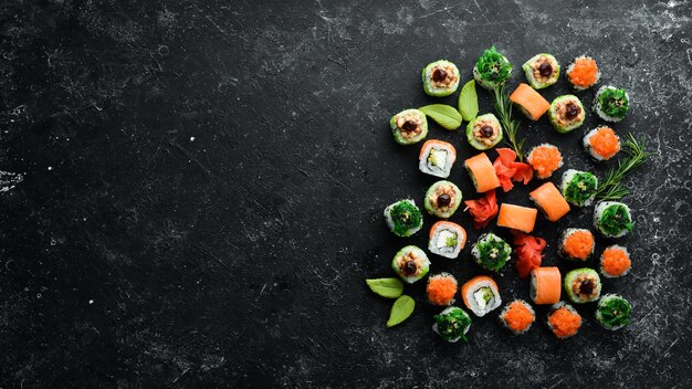 Foto gran conjunto de piezas de rollos de sushi sobre fondo de piedra negra vista superior espacio libre para el texto