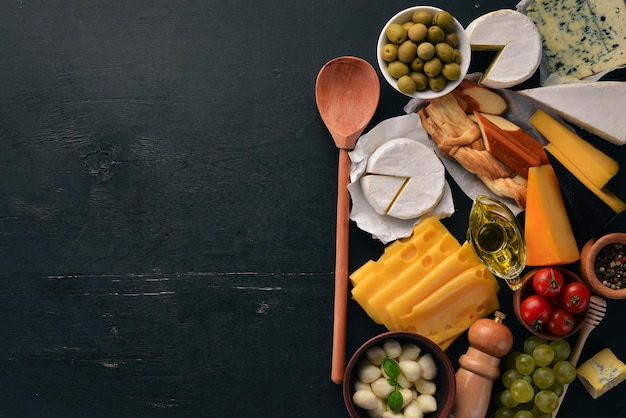 Un gran conjunto de quesos Mozzarella queso azul queso brie maasdam Vista superior Sobre un fondo de madera negra Espacio libre para su texto