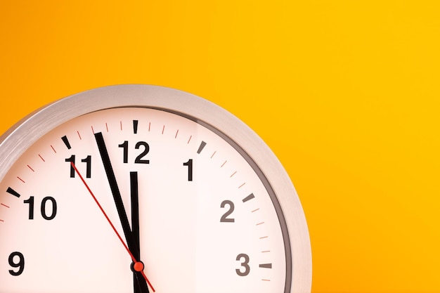 Gran despertador blanco, números negros, ajuste la hora en una mesa. Reloj sobre fondo amarillo aislado.