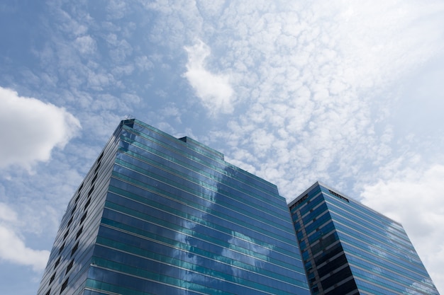 Gran edificio de oficinas de vidrio con cielo azul y nubes blancas