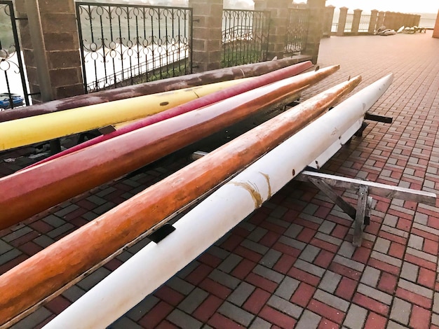 Gran equipo de botes de remo multiplaza largos para deportes acuáticos en la playa sobre baldosas de piedra