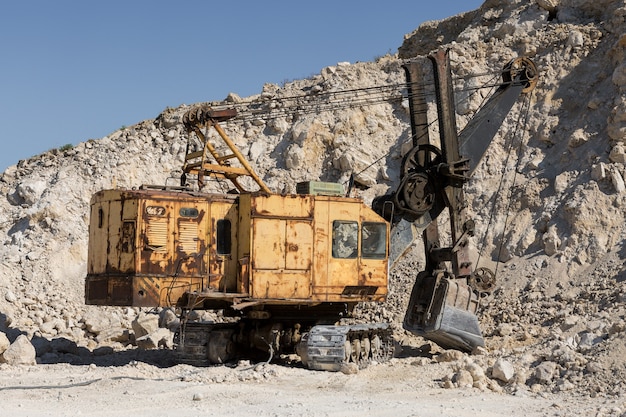 Una gran excavadora de orugas amarilla está extrayendo roca en una cantera.