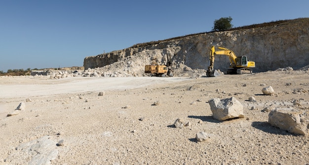 Una gran excavadora de orugas amarilla está extrayendo roca en una cantera.