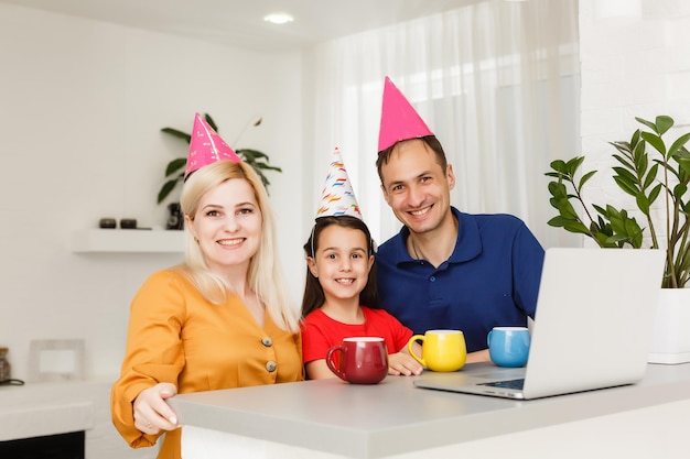 Gran familia celebra cumpleaños en línea. Mamá, papá, niños en casa, videollamadas portátiles, autoaislamiento. Gadgets de nueva tecnología de fiesta. Coronavirus en cuarentena.