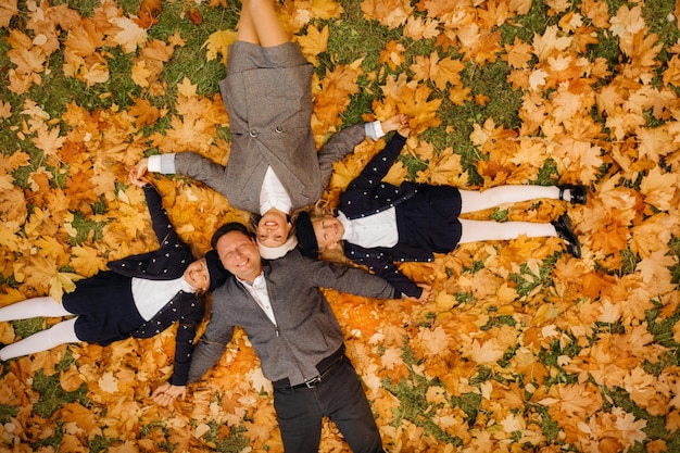 Una gran familia cogidos de la mano yace en un parque de otoño Gente feliz en el parque de otoño