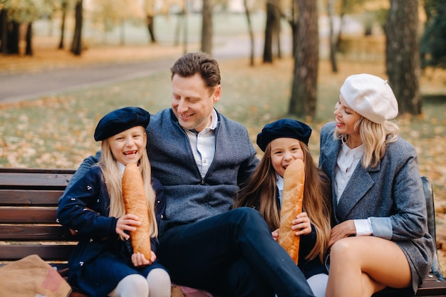 Una gran familia está sentada en un banco en un parque de otoño Gente feliz en el parque de otoño