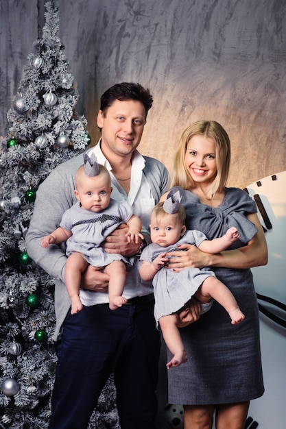 Una gran familia feliz con hijos gemelos en el interior de la casa de Año Nuevo en el fondo de un árbol de Navidad