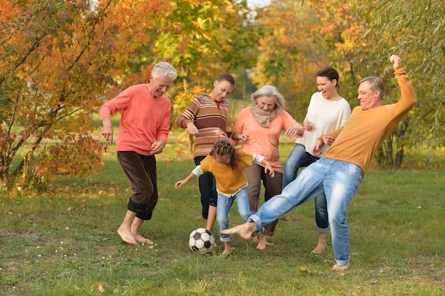 Foto gran familia feliz jugando al fútbol en el parque de otoño