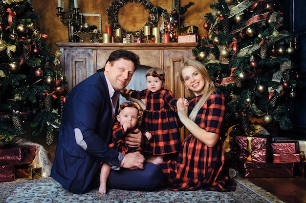 Una gran familia feliz con sus hijos en el interior de la casa de Año Nuevo junto a la chimenea junto al árbol de Navidad