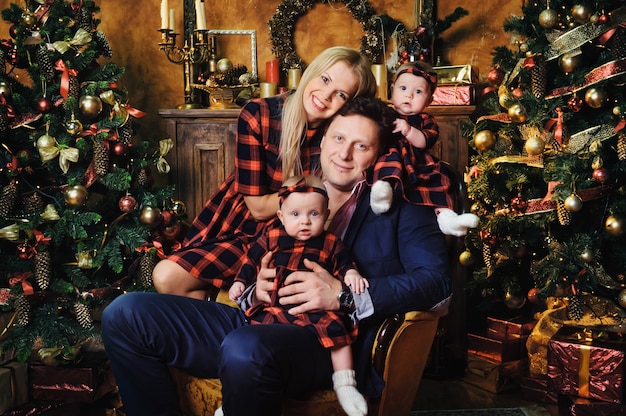 Una gran familia feliz con sus hijos en el interior de la casa de Año Nuevo junto a la chimenea junto al árbol de Navidad