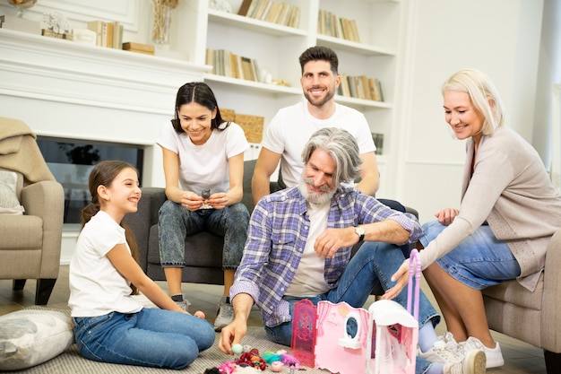 Gran familia multigeneracional feliz jugando con un niño lindo en la sala de estar en casa