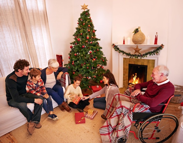 Gran familia Navidad y regalos o regalos con niños, padres y abuelos juntos para el amor, el cuidado y la celebración. Hombres, mujeres y niños en casa en la chimenea para celebrar las vacaciones.