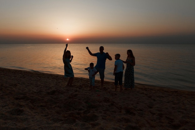 Gran familia en la playa siluetas de personas contra la puesta de sol personas cogidas de la mano