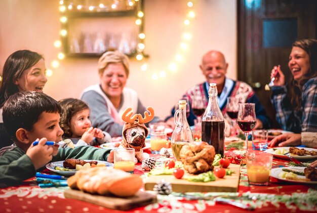 Gran familia de varias generaciones divirtiéndose en la cena de Navidad - Enfoque selectivo en la marioneta de renos