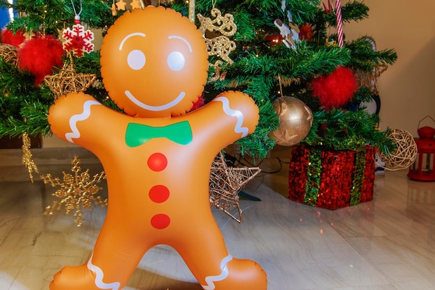 Gran figura hinchable de temporada de pan de jengibre ante un árbol de Navidad artificial iluminado.