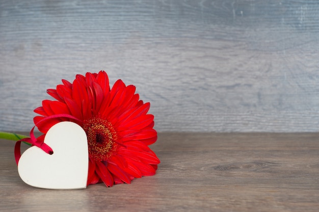 Gran flor roja con forma de corazón en la mesa de madera rústica