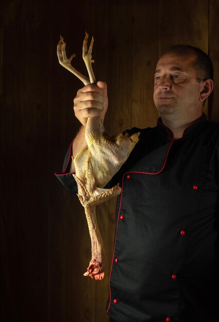 Gran gallo crudo en la mano del chef Presentación de un pollo antes de preparar un delicioso plato