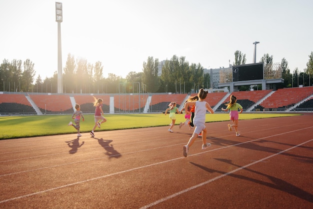 Un gran grupo de chicas se preparó al principio antes de correr en el estadio durante la puesta de sol Un estilo de vida saludable