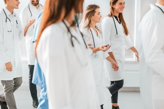 Un gran grupo de profesionales médicos atravesando el vestíbulo del hospital.