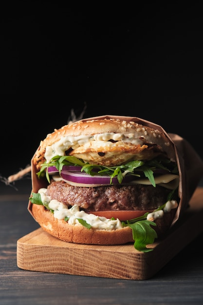 Gran hamburguesa a la plancha con verduras sobre una plancha de madera