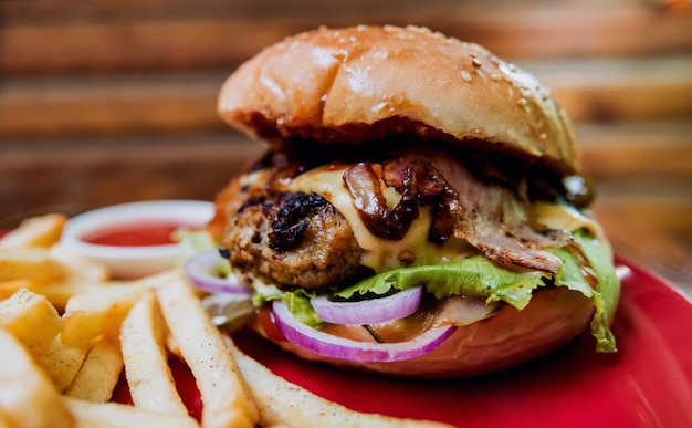 Gran hamburguesa con queso y patatas fritas en un plato.