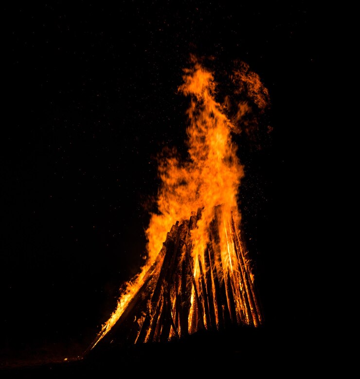 Gran hoguera contra el cielo nocturno oscuro. Llamas de fuego sobre fondo negro