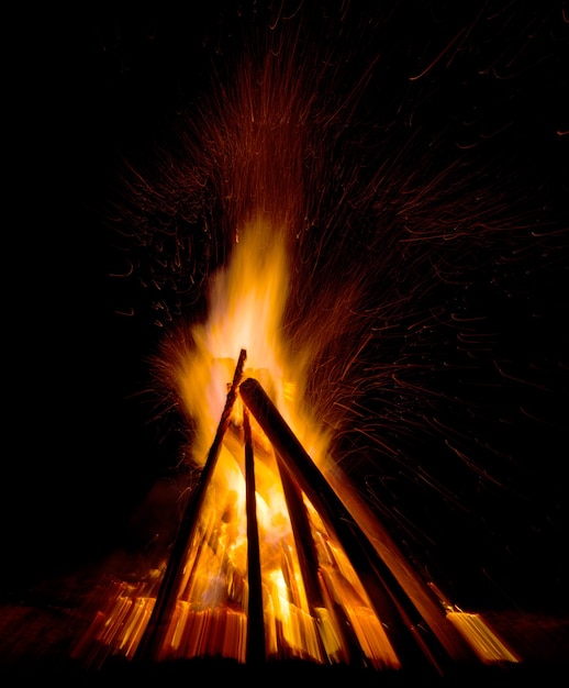 Gran hoguera contra el cielo nocturno oscuro. Llamas de fuego sobre fondo negro