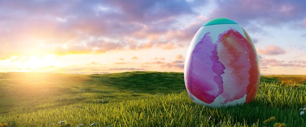 Foto gran huevo de pascua de color agua pintado en pascua al amanecer o al atardecer en un paisaje de pradera, fondo panorámico, con espacio de copia para su texto individual.
