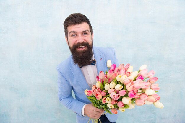 En gran humor novia novio en la fiesta de bodas hombre barbudo en pajarita con flores de tulipán cita de amor con flores Feliz cumpleaños ramo de primavera 8 de marzo día de la mujer Empresario maduro formal