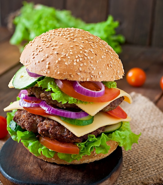 Gran jugosa hamburguesa con verduras y carne en una mesa de madera en estilo rústico