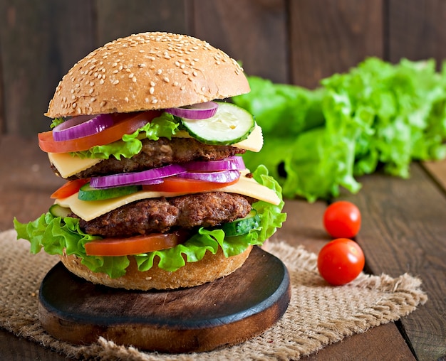 Gran jugosa hamburguesa con verduras y carne en una mesa de madera en estilo rústico