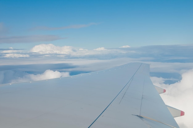 Gran lado de ala larga de un avión aerodinámico moderno que transporta pasajeros sobre el hermoso cielo azul que viaja