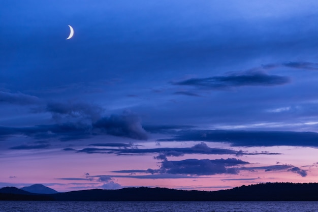 Gran luna en el cielo azul sobre el lago en la noche