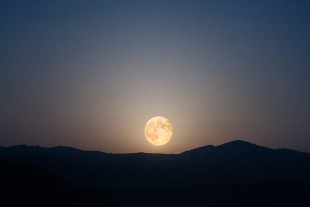 Gran luna en el cielo nocturno con muchas estrellas sobre la cordillera