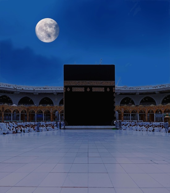 una gran luna está brillando en el cielo por encima de un edificio mecca Kaaba