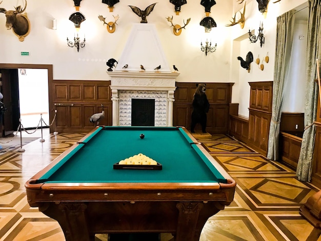 Una gran mesa de billar de madera enorme y cara para jugar al billar en una habitación con chimenea
