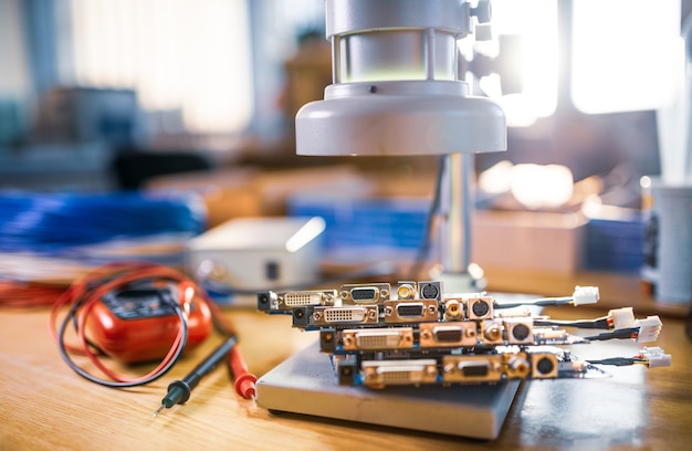 Un gran microscopio electrónico moderno y microcircuitos integrados se apilan en la placa de prueba para prepararse para la investigación de componentes electrónicos en un laboratorio científico.