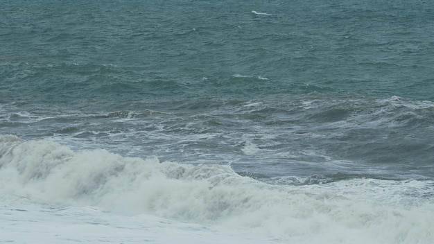 Una gran ola salpicando olas con textura y el viento rociando una poderosa ola de tsunami espuma blanca en el viento