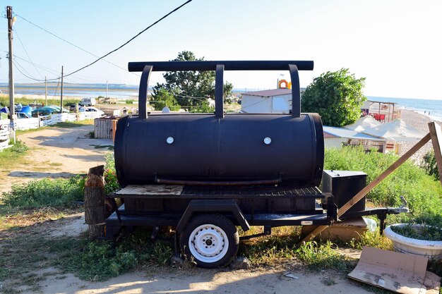 Una gran parrilla para asar carne sobre ruedas se encuentra en la playa para cocinar comida callejera