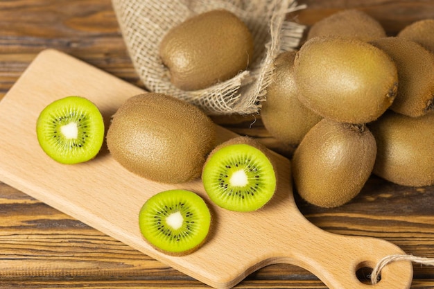 Gran parte de la mitad del kiwi marrón exótico en una tabla de cortar de bambú y una mesa de madera Enfoque selectivo