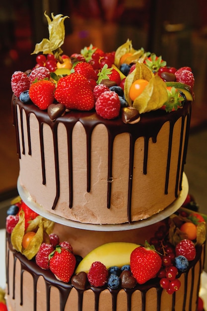 Un gran pastel de bodas de tres niveles en un banquete de bodas decorado con fruta fresca y chocolate Enfoque suave Primer plano