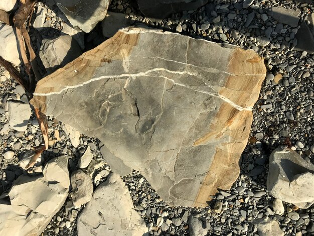 Una gran piedra se encuentra sobre un guijarro de mar en la playa pieza de roca