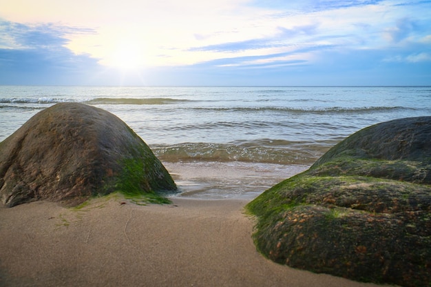 Gran piedra en la playa de arena frente al mar con nubes en el cielo Escandinavia