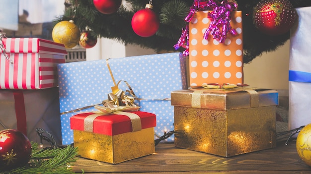 Gran pila de coloridas cajas de regalo y adornos en el piso bajo el árbol de Navidad