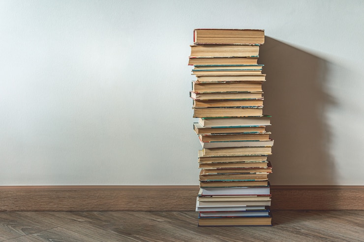 Foto gran pila de libros viejos sobre pared blanca