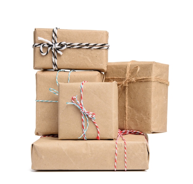 Gran pila de regalos envueltos en papel kraft marrón y atados con cuerda, cajas aisladas en blanco