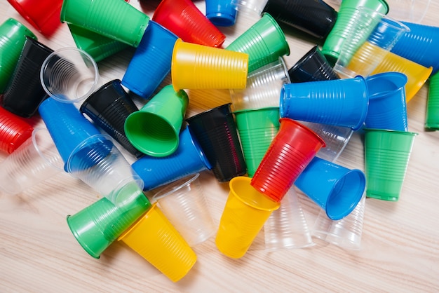 Una gran pila de vasos de plástico multicolores esparcidos por el suelo. Contaminación del medio ambiente por desechos humanos.