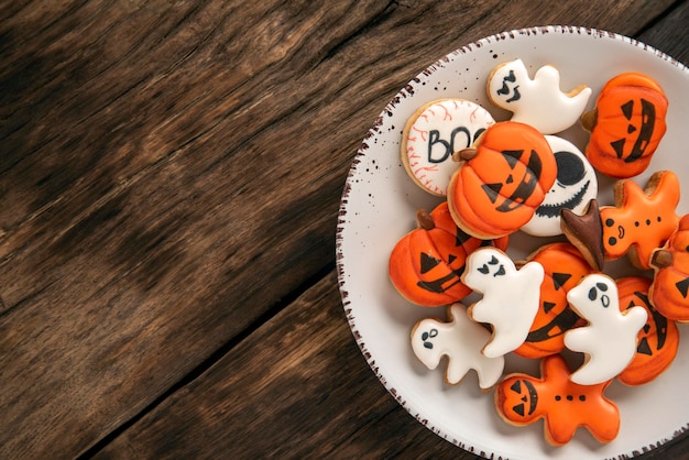 Foto gran plato de galletas de halloween de color naranja brillante en forma de fantasmas de calabaza en una mesa de madera lugar para el texto vista superior